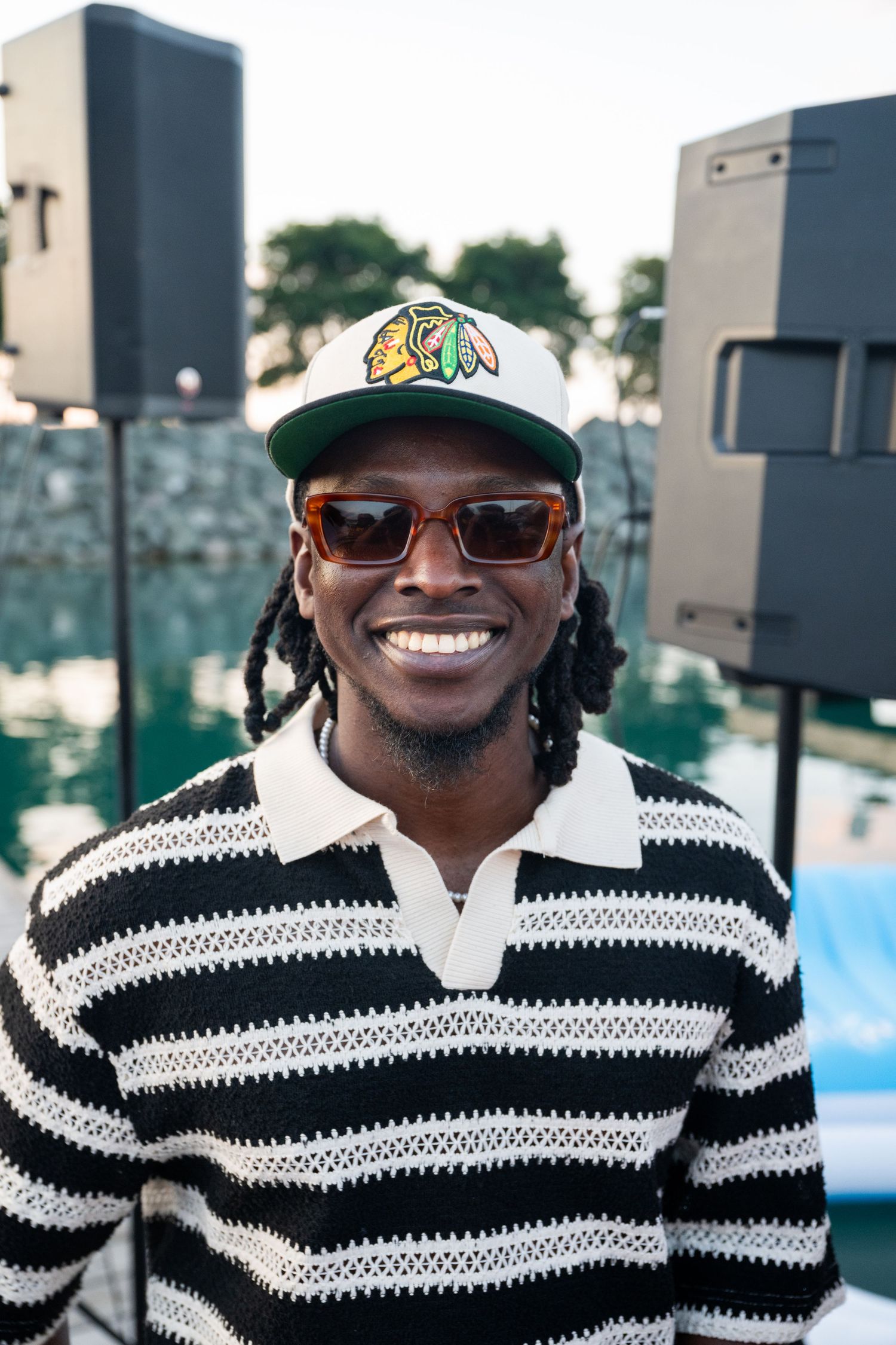 Person wearing a black and white striped sweater and colorful cap smiling outdoors.