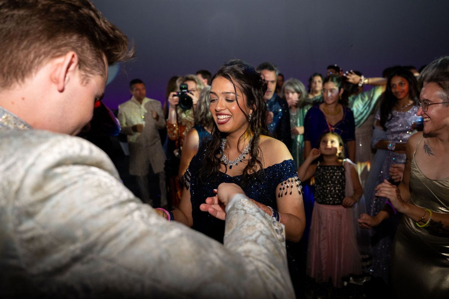 Wedding guests dance and celebrate together on a crowded dance floor at an evening reception party.