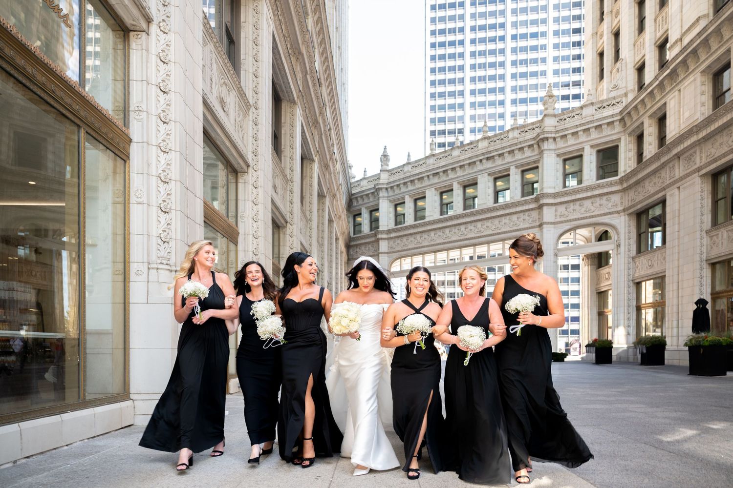 Wedding party in formal attire poses together against elegant stone architecture in Chicago.