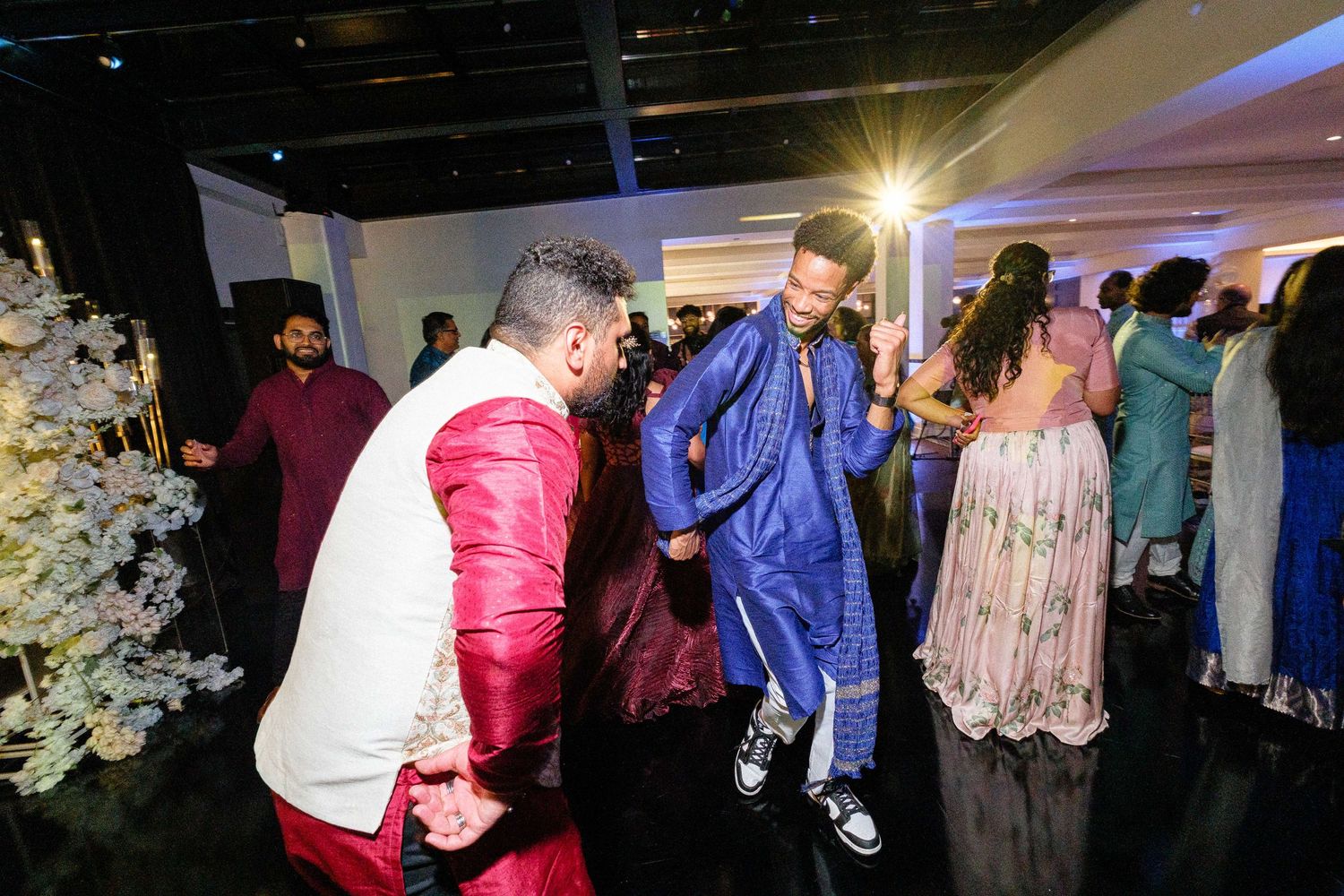Festive dance party scene with guests moving on the dance floor under ambient lighting.