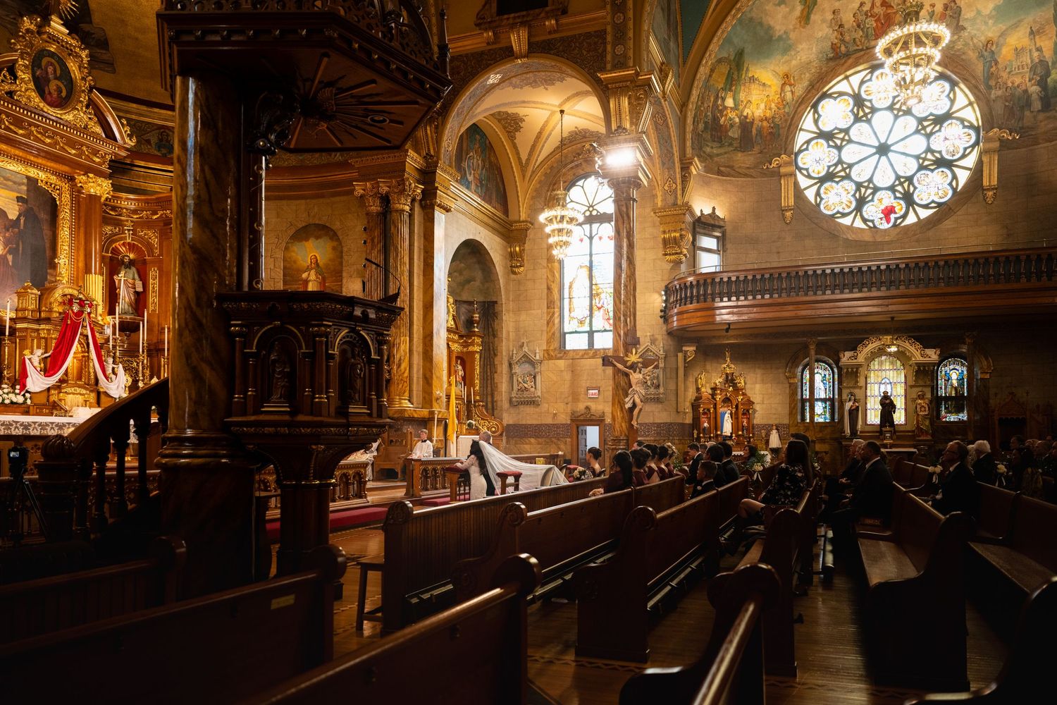 Ornate interior of historic synagogue with wooden pews, stained glass windows, and elegant chandeliers illuminating the space.