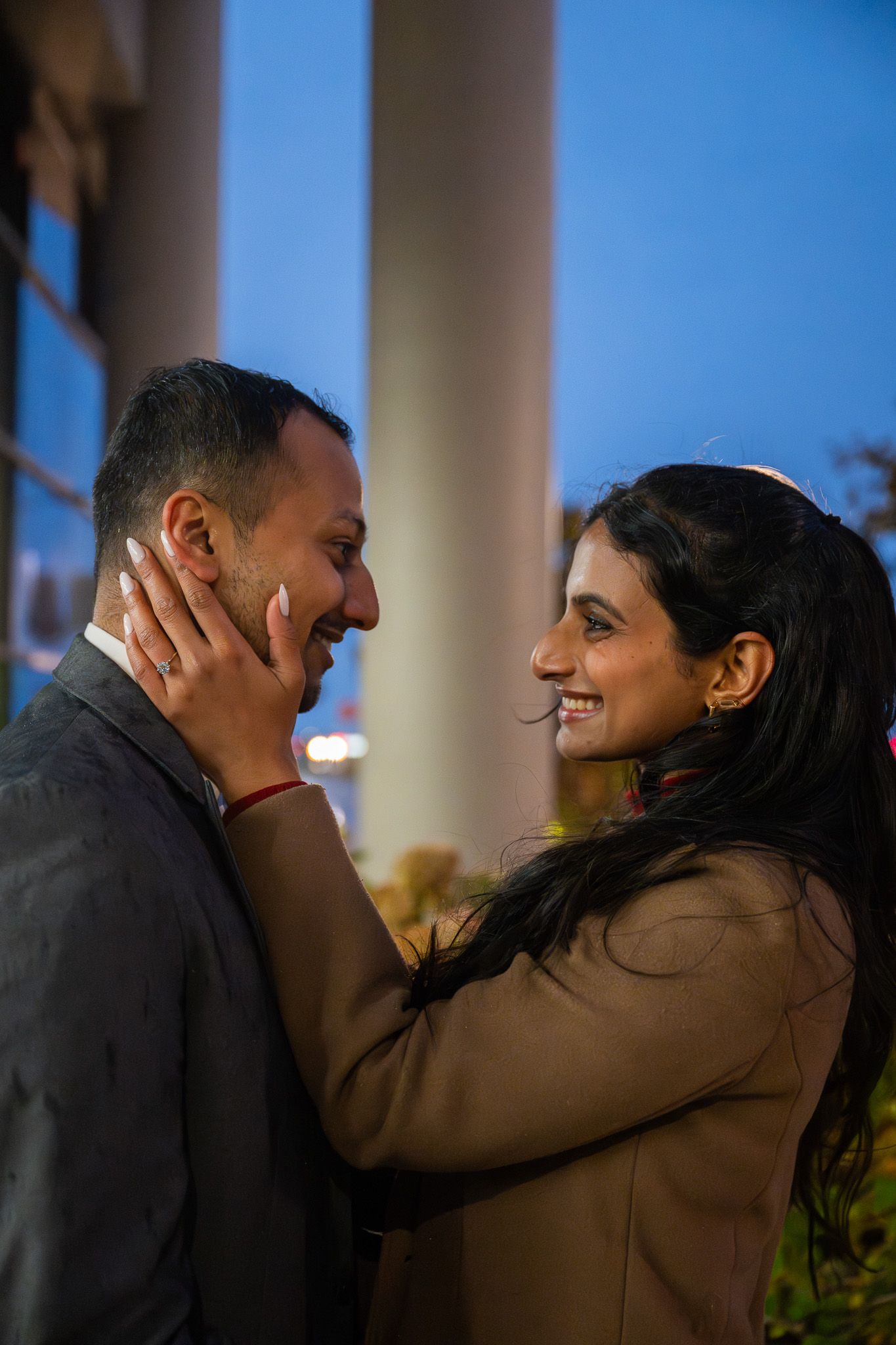 Romantic couple sharing an intimate moment outdoors at dusk with gentle smiles.
