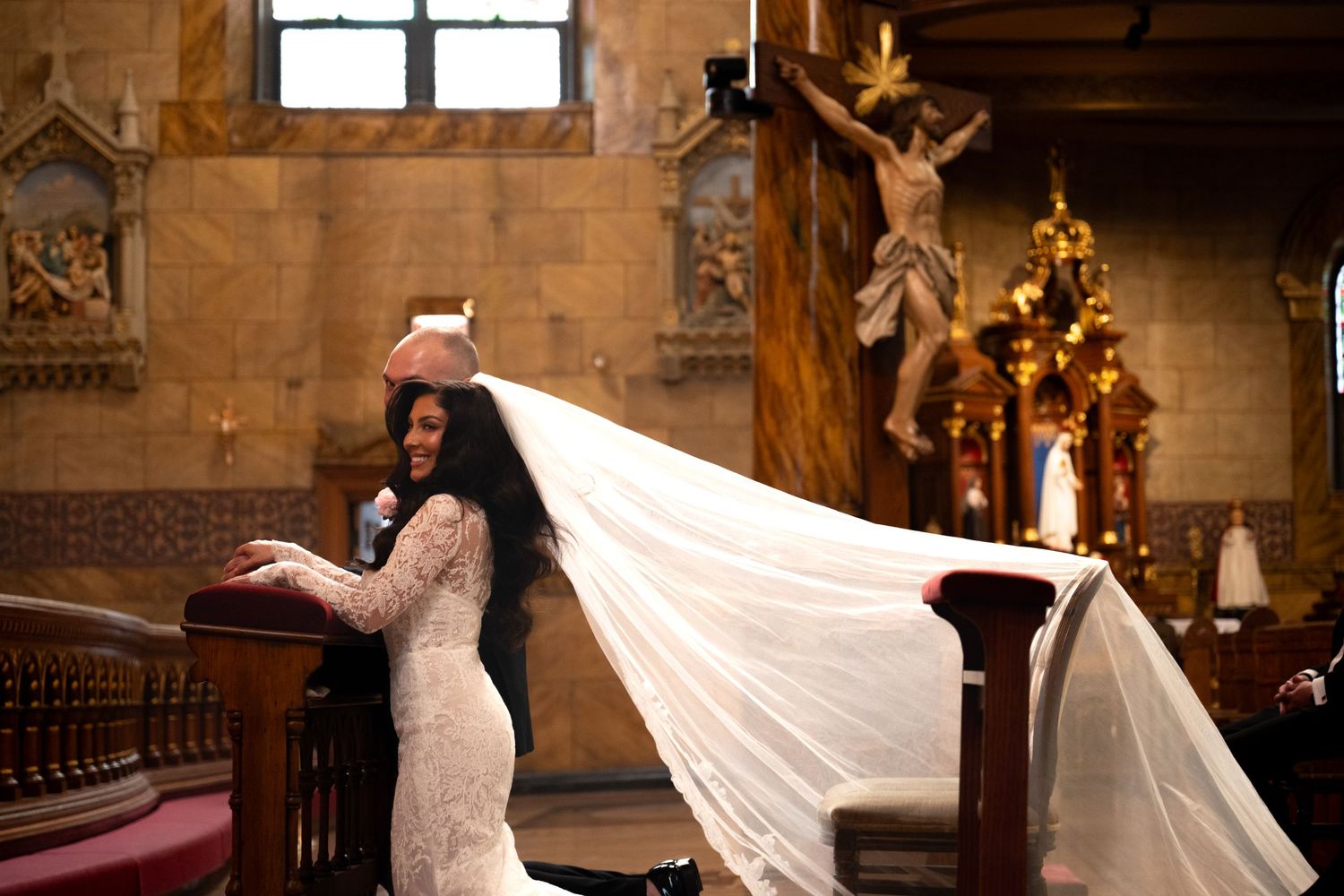 A couple shares an intimate dance moment in a grand church setting with ornate decorations and warm lighting.