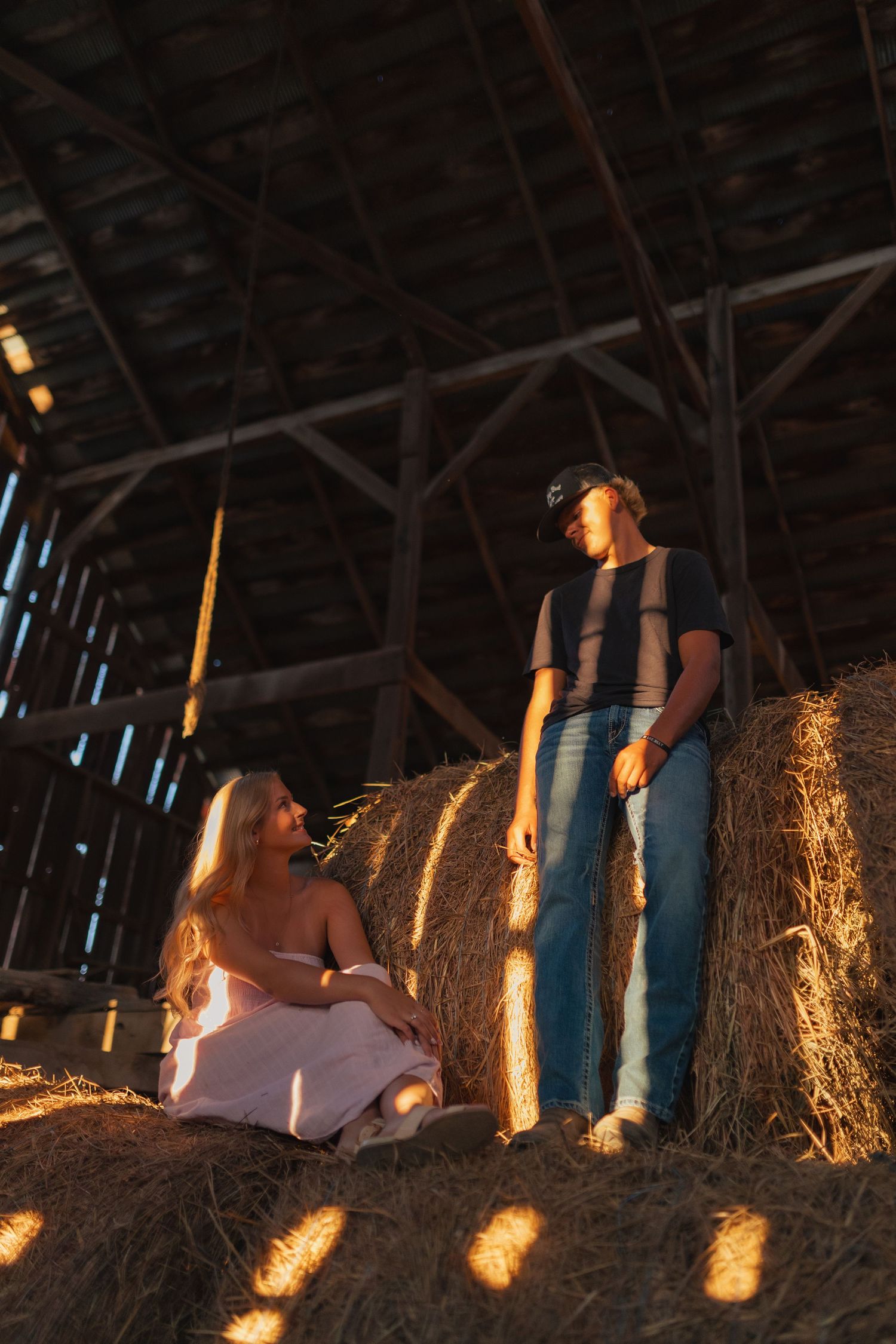 A couple in a rustic barn on hay bales at sunset