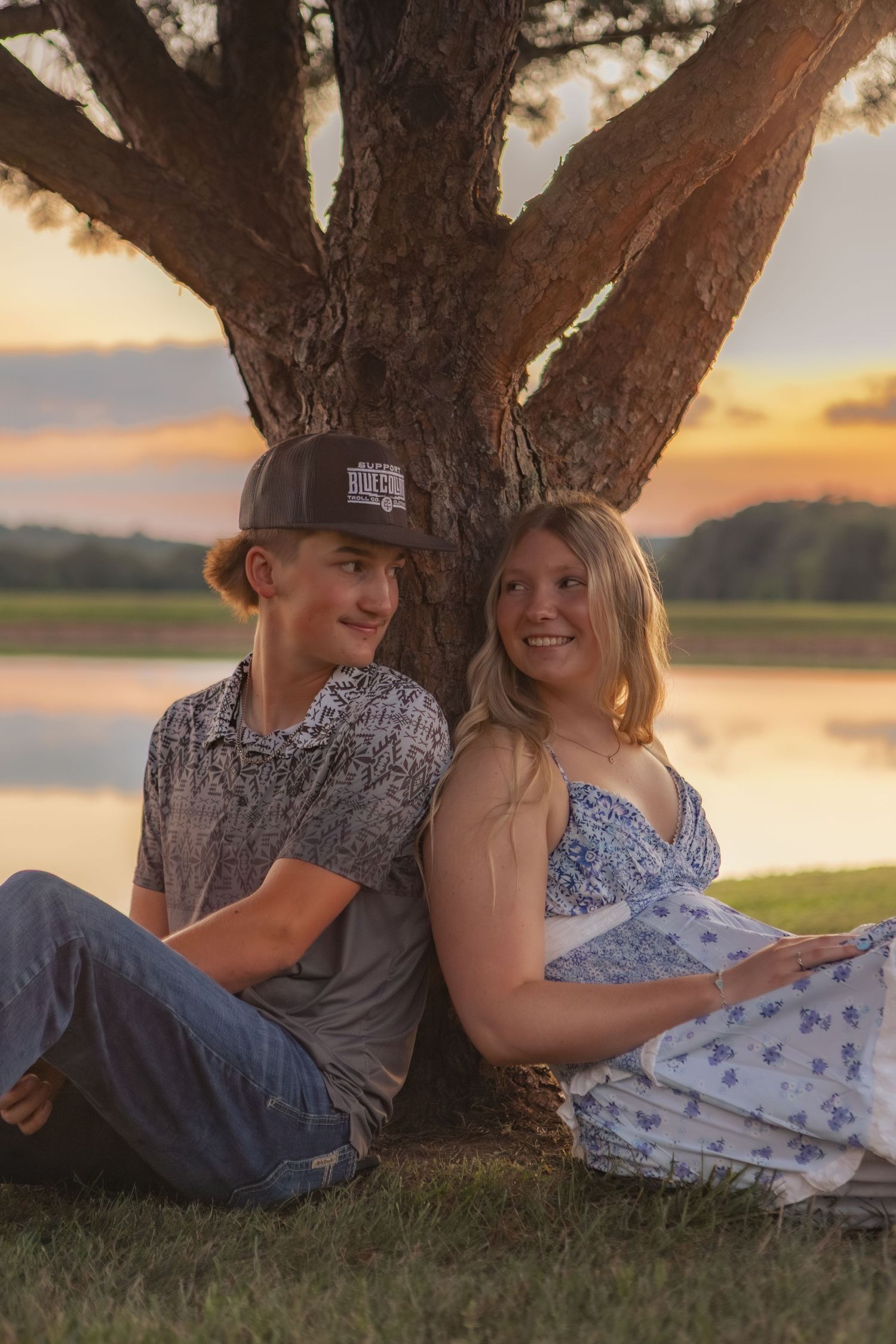 Girl and guy couple smile under a tree at golden hour in the Midwest.