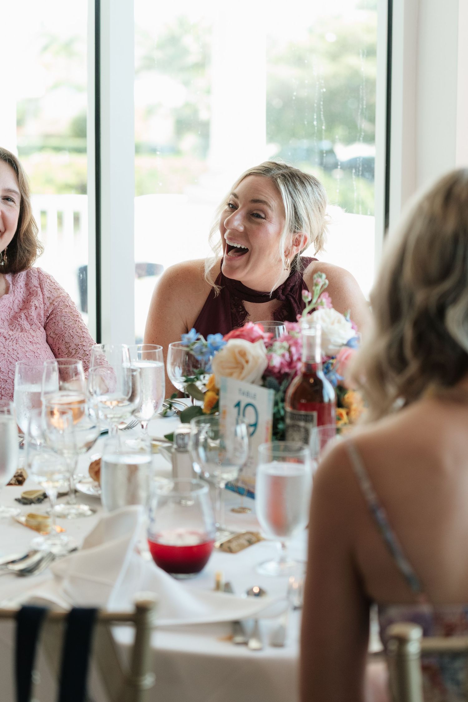 A group of guests sharing laughter and conversation around an elegant dining table at a reception.