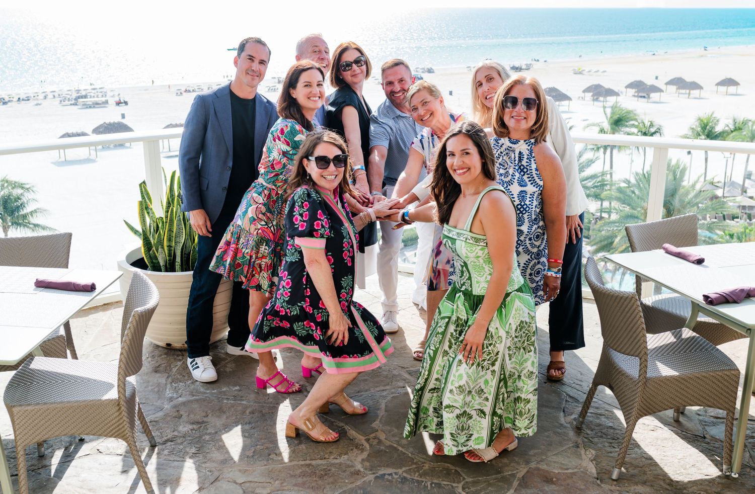 Group of friends posing together at a beachfront restaurant terrace on a sunny day.
