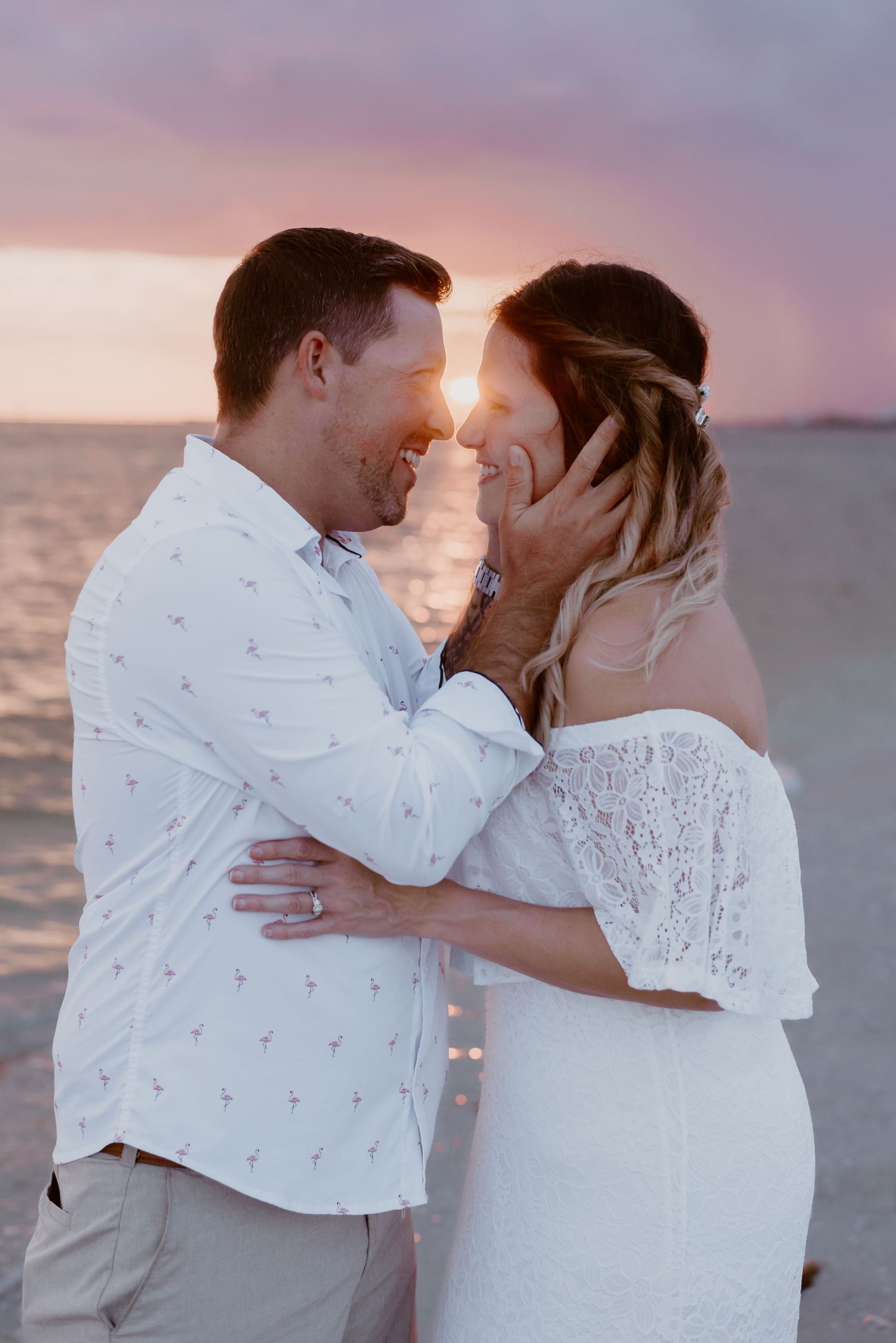 Romantic couple embracing on beach during sunset with glowing sun between them as they share intimate moment.