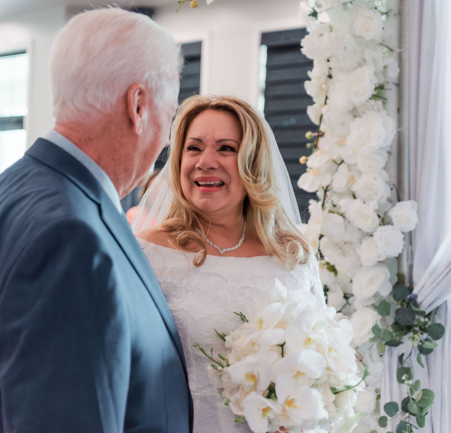 Candid moment captured at wedding ceremony with white floral decorations and elegant setting.