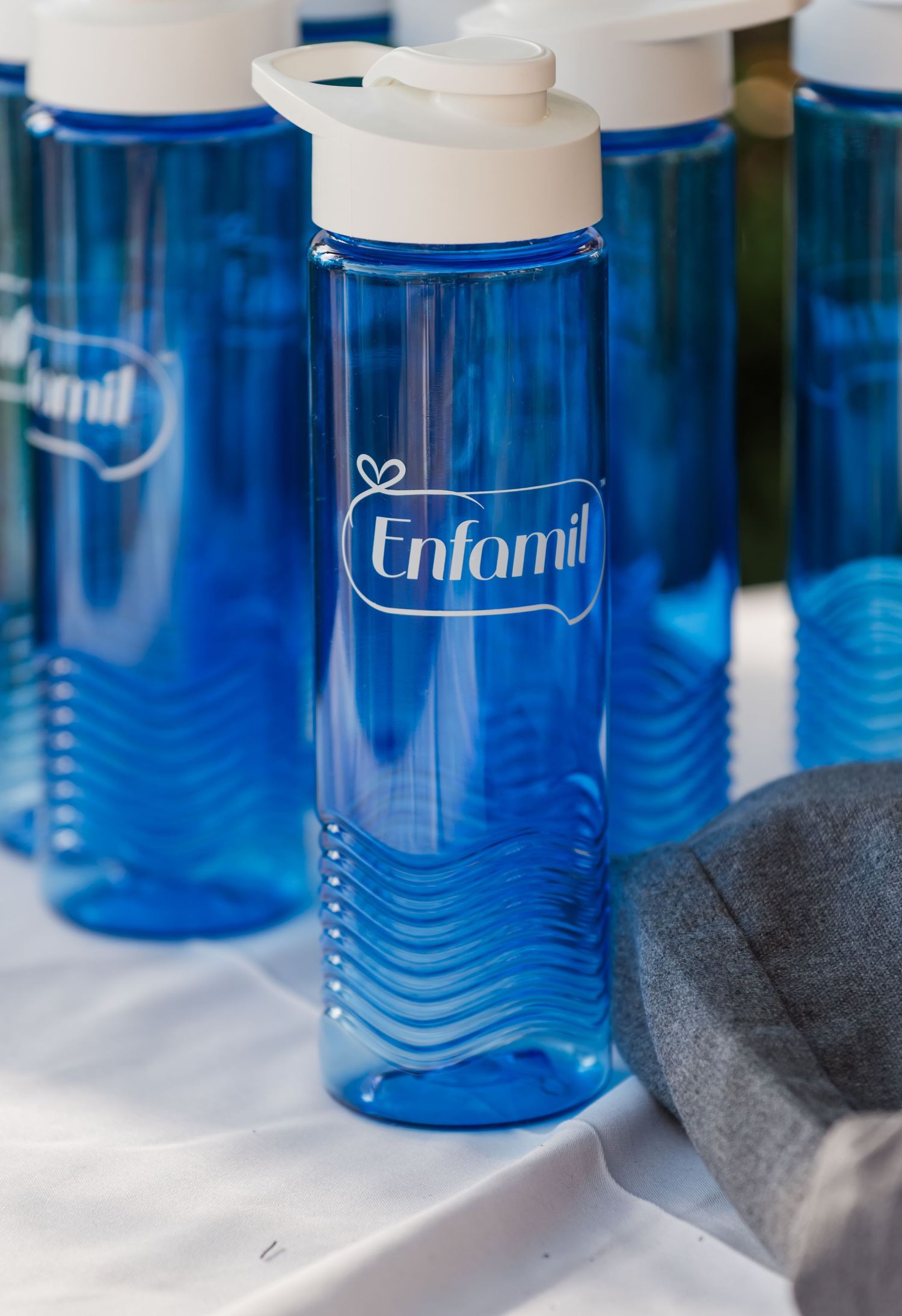Blue Enfamil branded reusable water bottles with white flip-top lids displayed on a white surface.