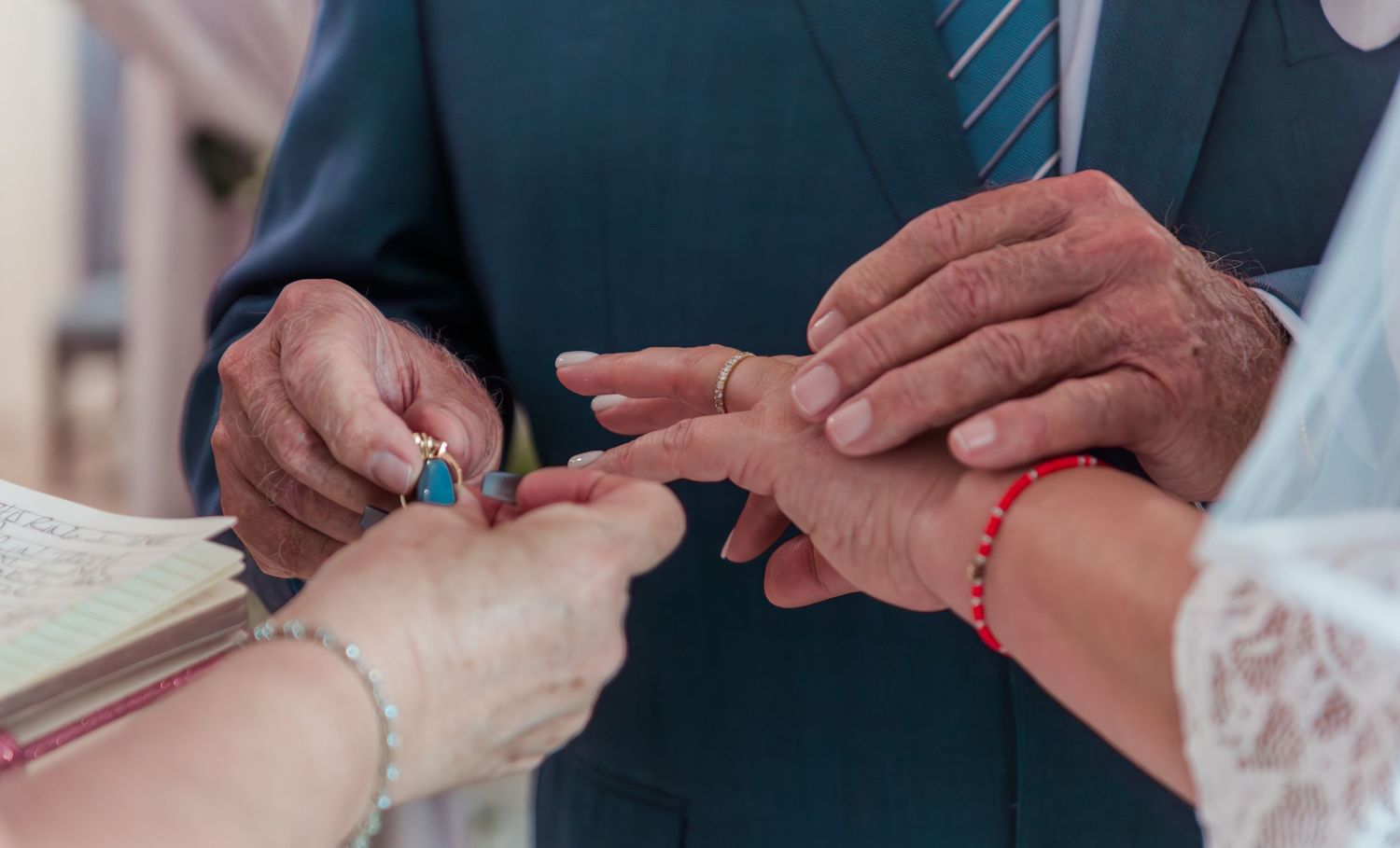 Two hands are exchanging rings during a formal ceremony, with close-up shots showing different angles of the exchange.