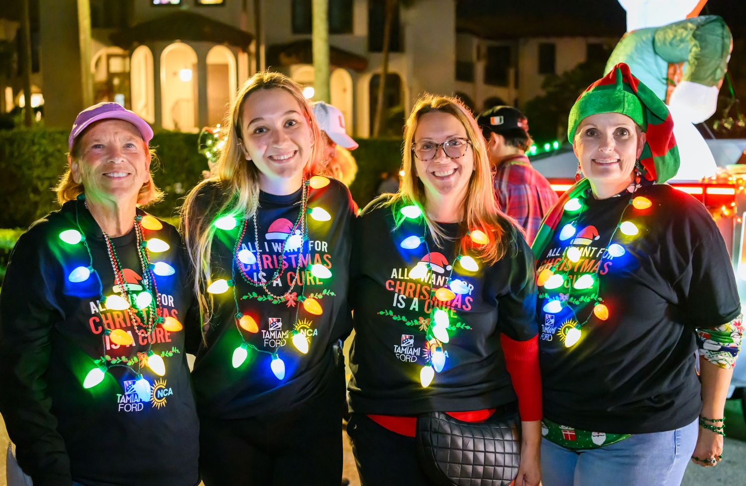 Group wearing festive Christmas light necklaces at nighttime holiday gathering.