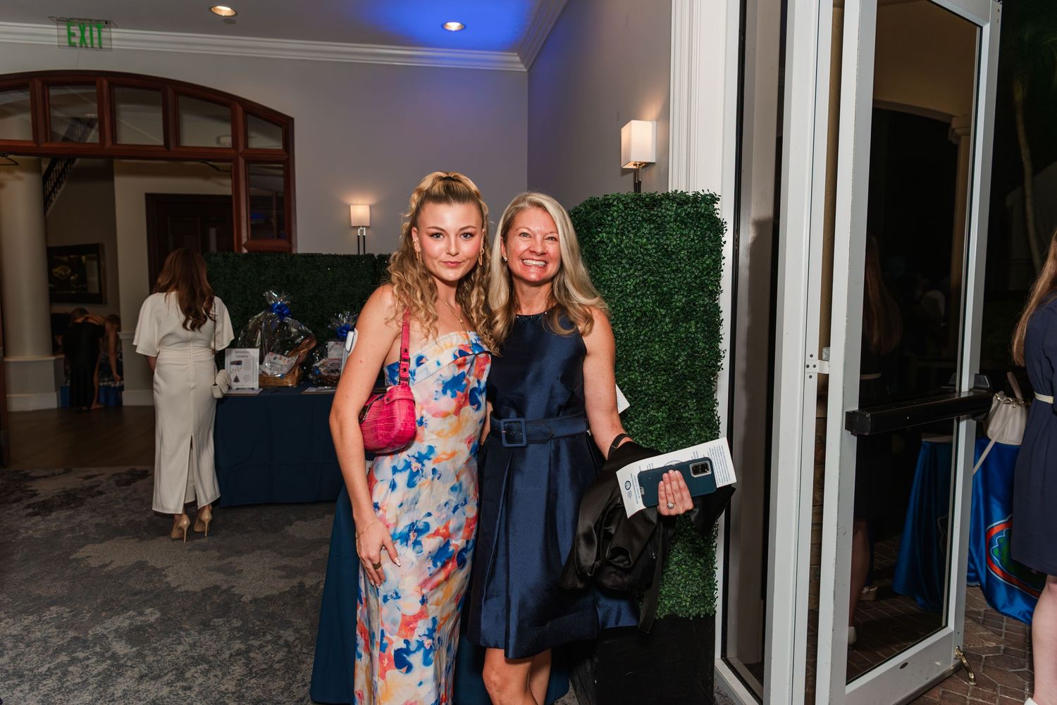 Guests mingle and socialize at an elegant evening event with blue lighting and indoor decor.