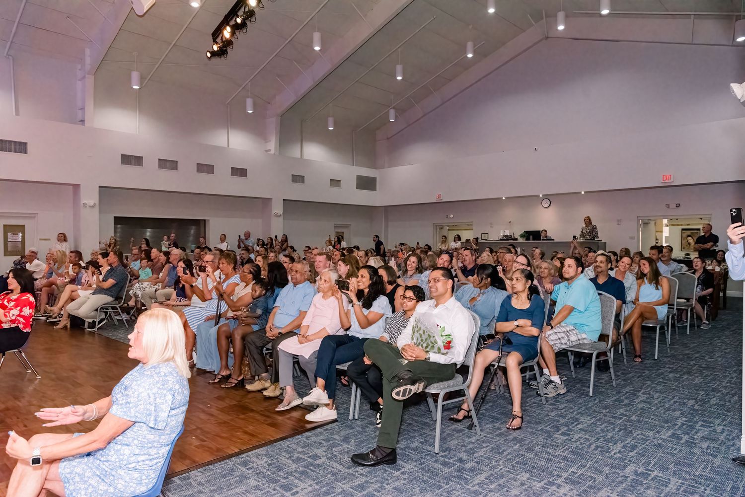 A panoramic view of a large auditorium filled with seated attendees during an indoor event or meeting.
