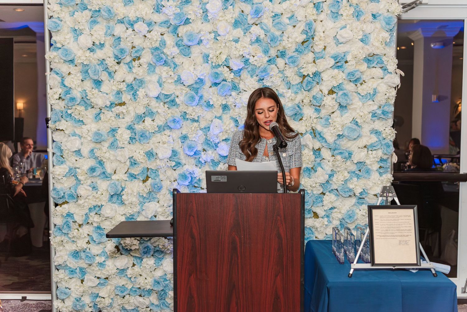 Reception area with floral wallpaper and dark wooden furniture against a blue and white patterned background.
