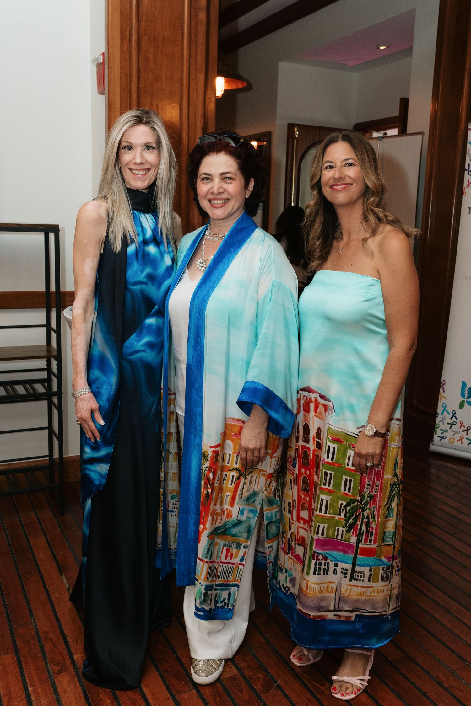 Group photo showing people wearing colorful silk scarves with cityscape designs in an indoor setting.
