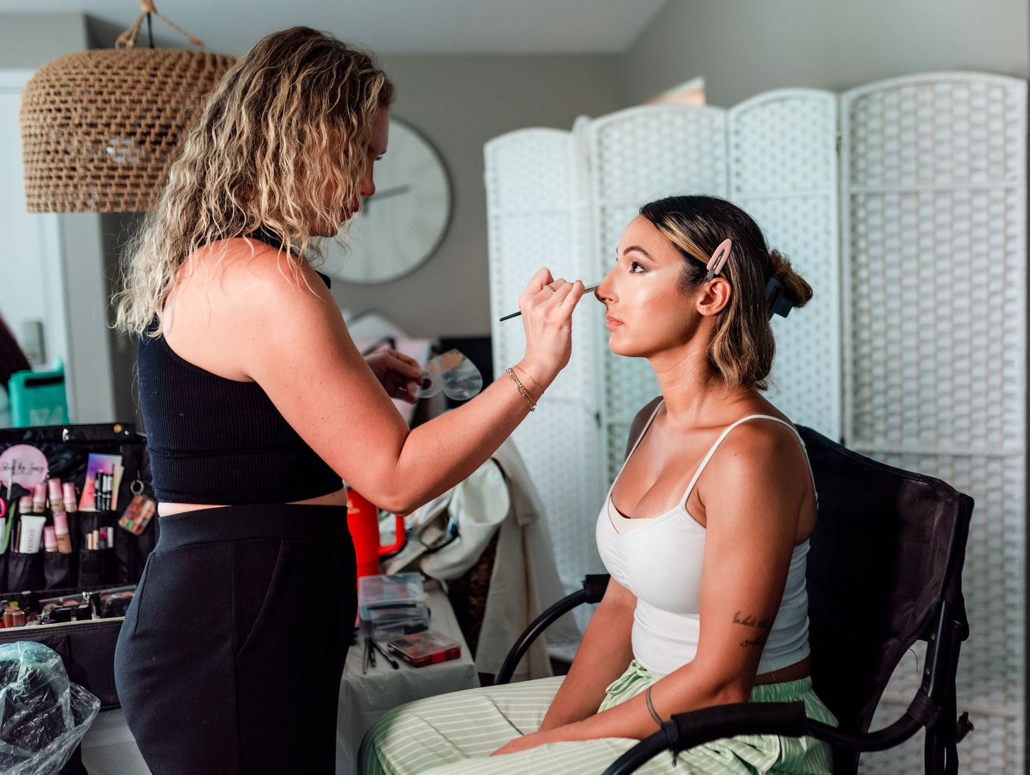 A series of photos showing a person getting their makeup professionally applied while sitting in a white chair.