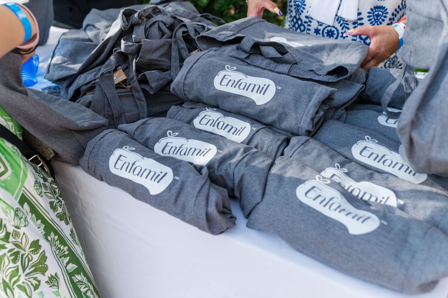 Gray Enfamil branded bags displayed on a table at an outdoor event.