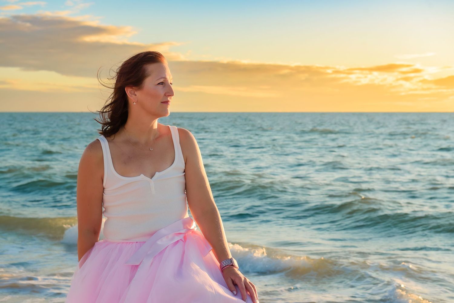A series of beachside photos at sunset showing someone in a pink dress walking along the ocean shore.
