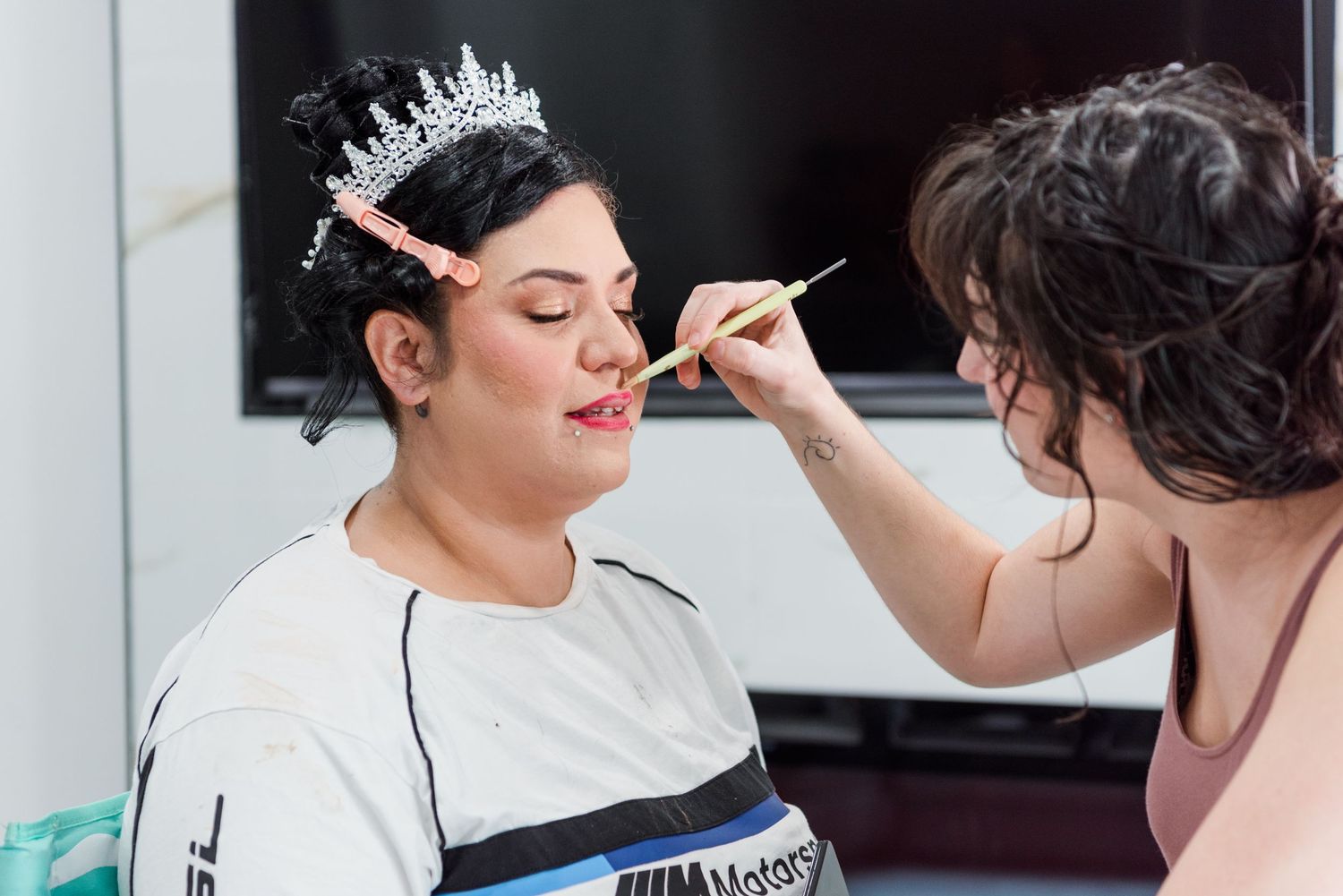 Makeup artist applies cosmetics to model's face during professional beauty session at bright makeup studio.