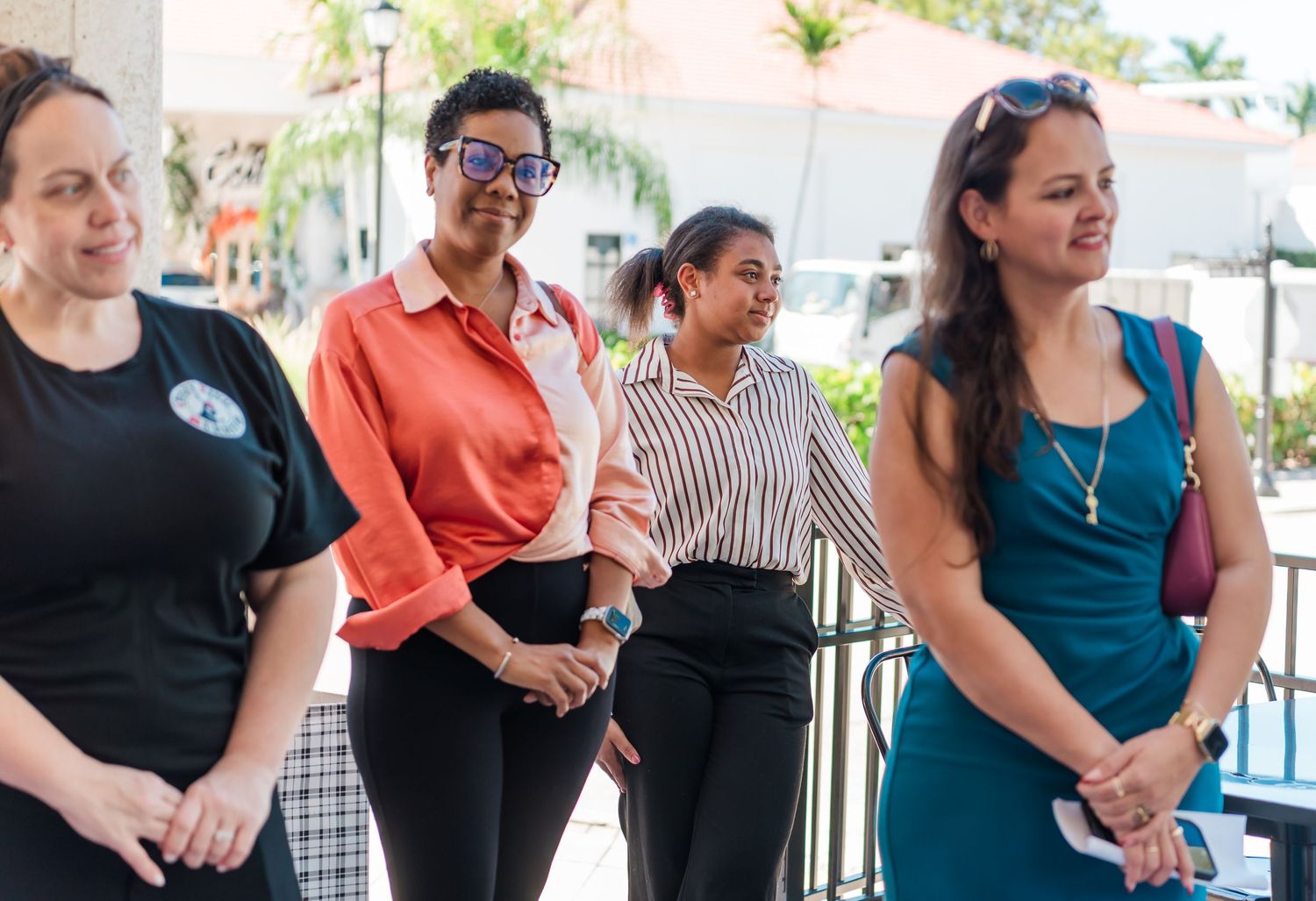 A group of people stand together in a casual outdoor setting wearing business casual attire.