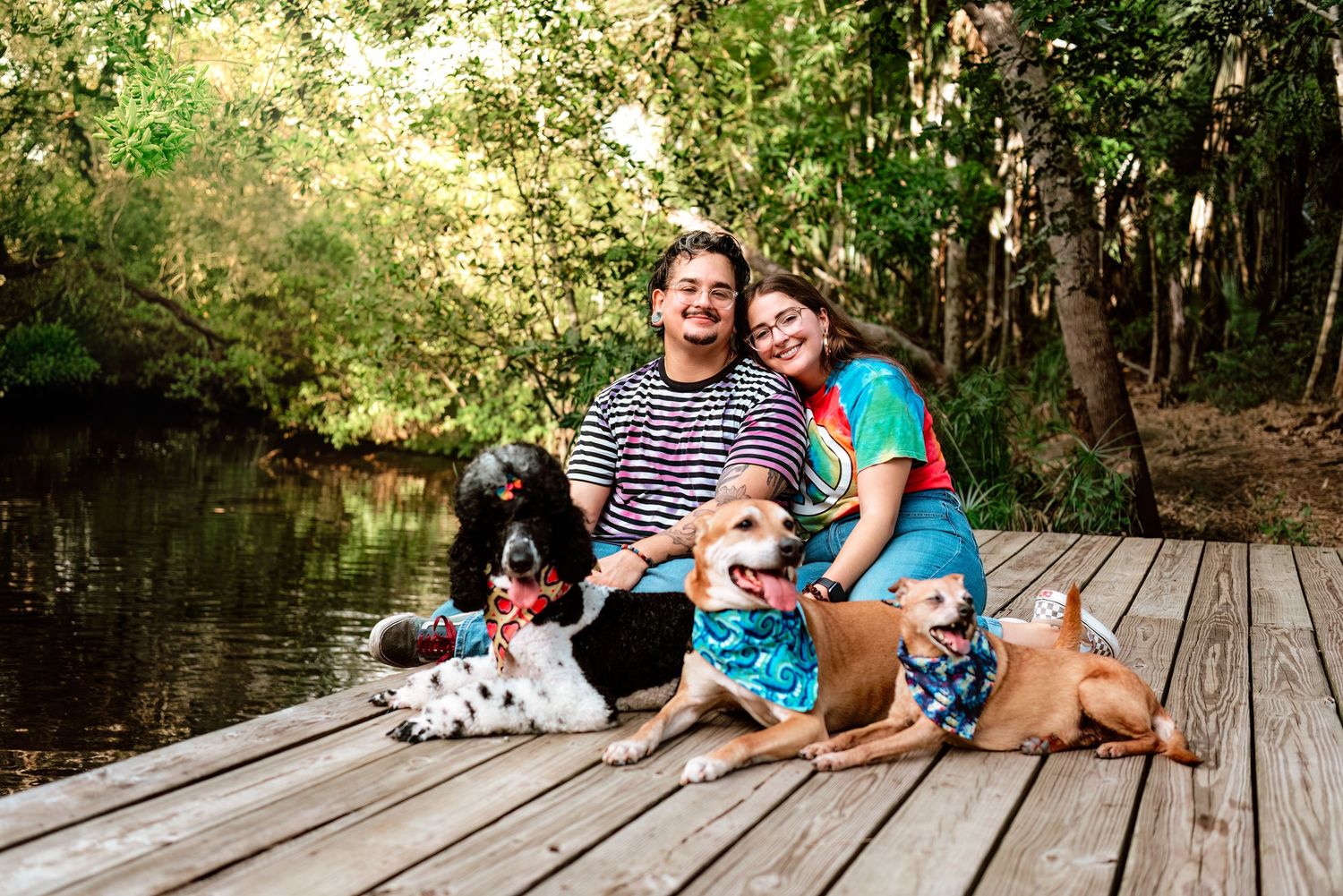 Family and dog relaxing together on wooden dock by peaceful lake on sunny afternoon.