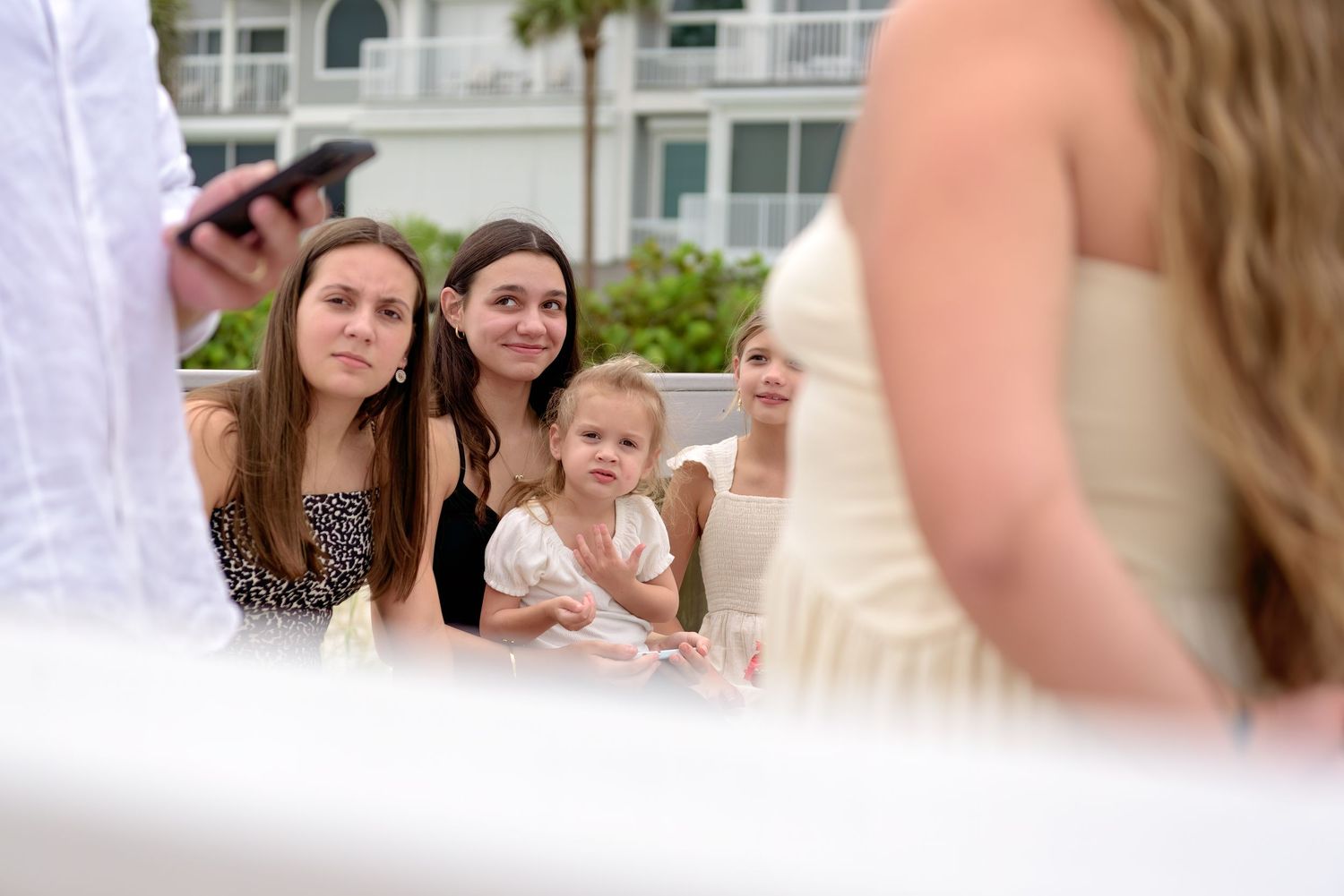 Blurred wedding photos showing people celebrating at an outdoor reception venue with palm trees visible in background.