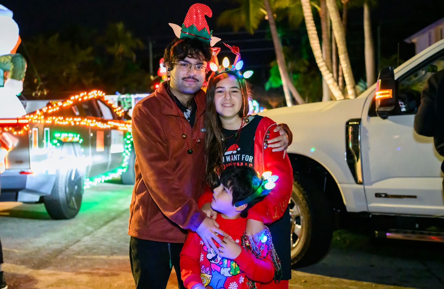 People enjoying a festive outdoor gathering with colorful lights and decorations at night.