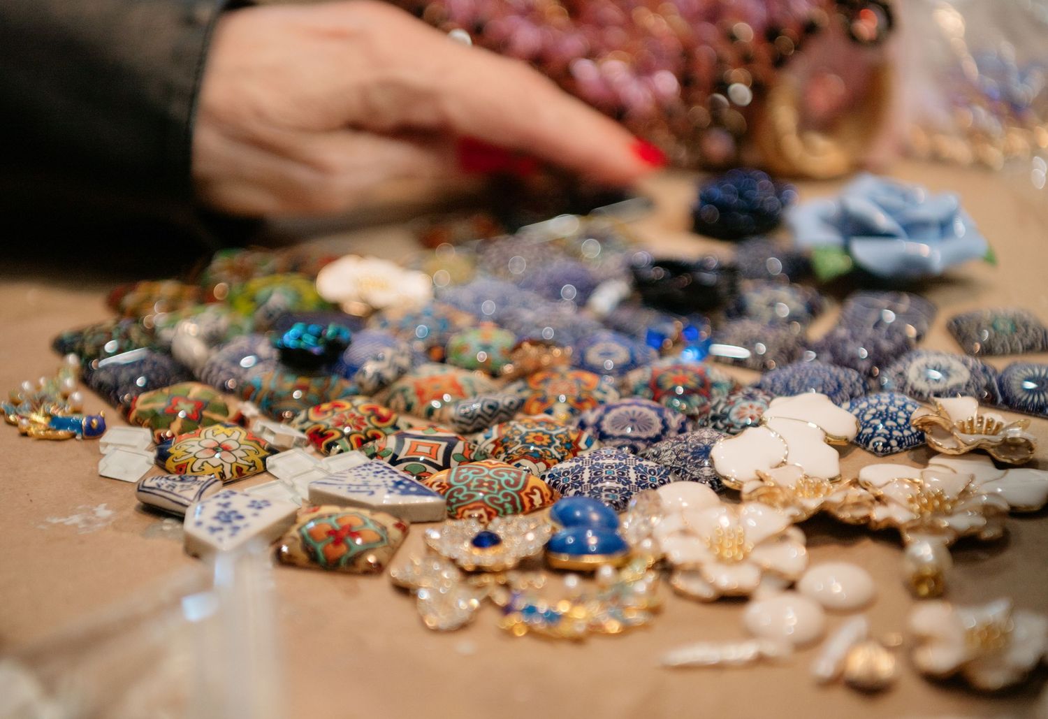Close-up of colorful beaded brooches and mosaic jewelry pieces spread across a work table.