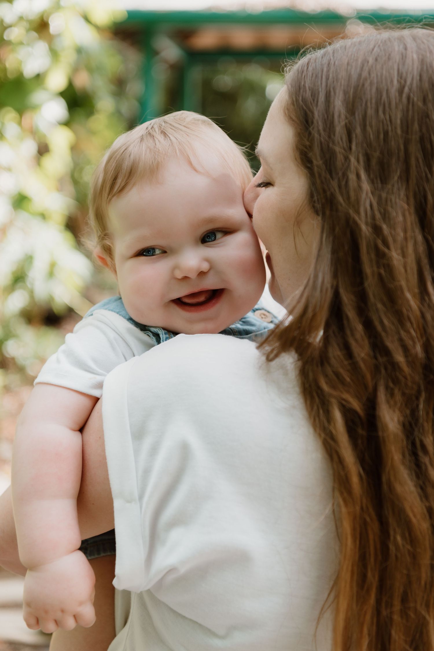 Sweet series of close-up shots capturing joyful interactions and kisses between parent and smiling baby outdoors.