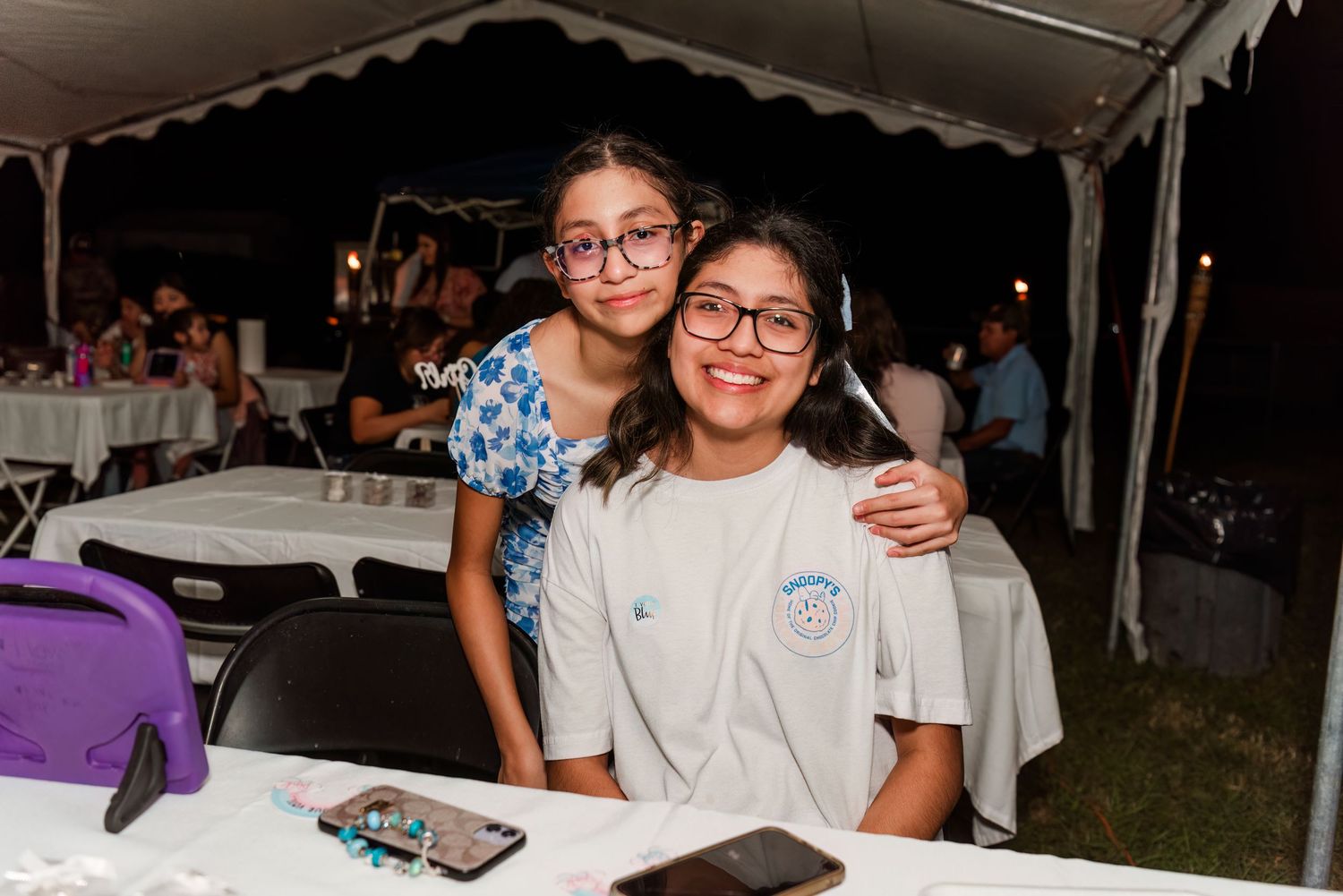 People enjoying themselves at an outdoor event with white tents and tables visible in the background.