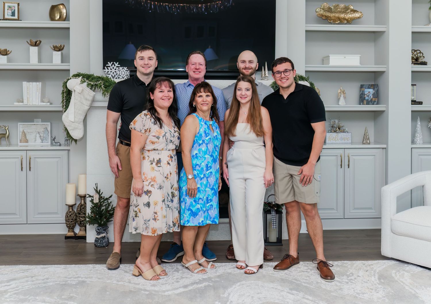 A cheerful family of seven poses together in a beautifully decorated living room during the holiday season.