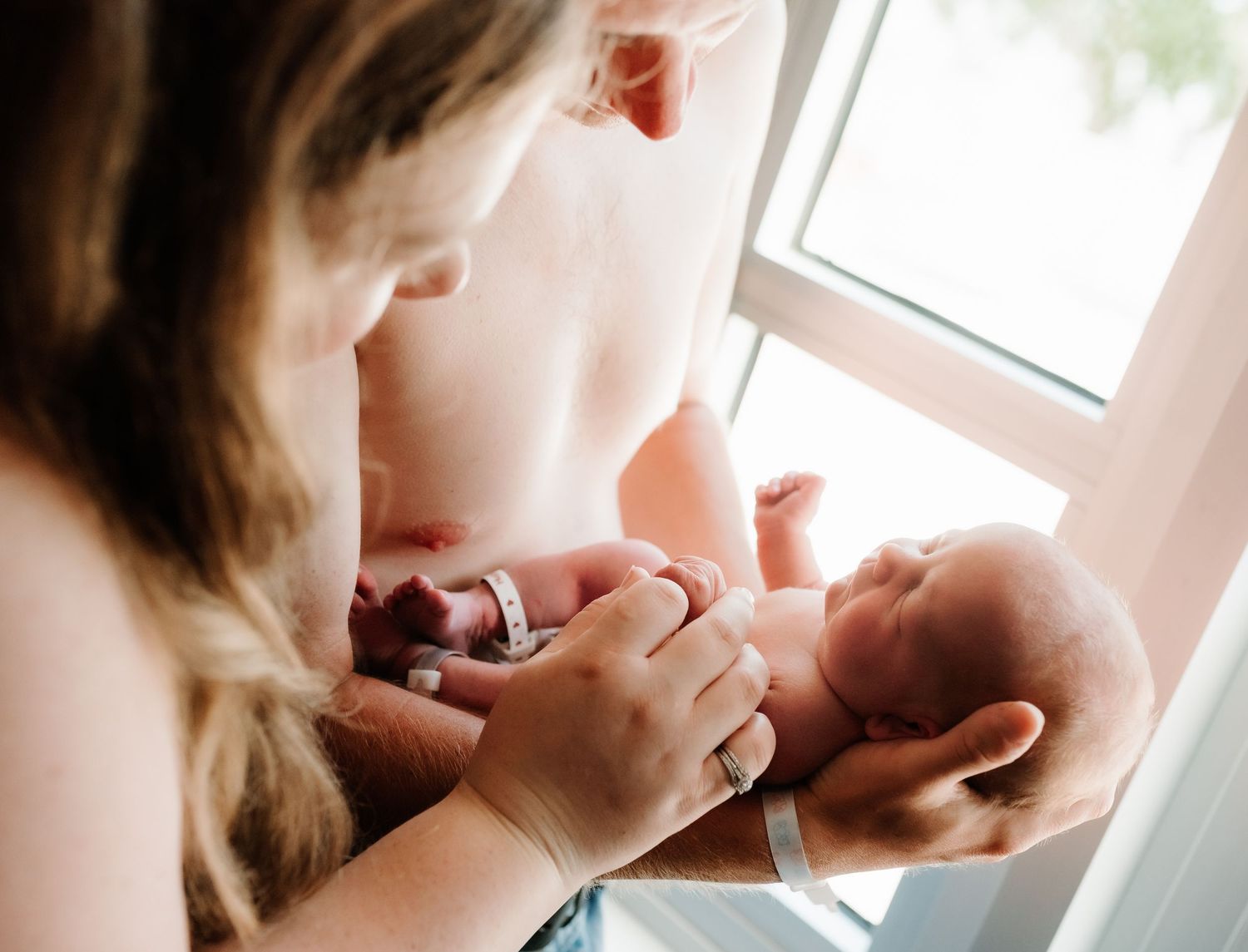 Close-up photography of a sleeping newborn baby captured in soft natural window light.