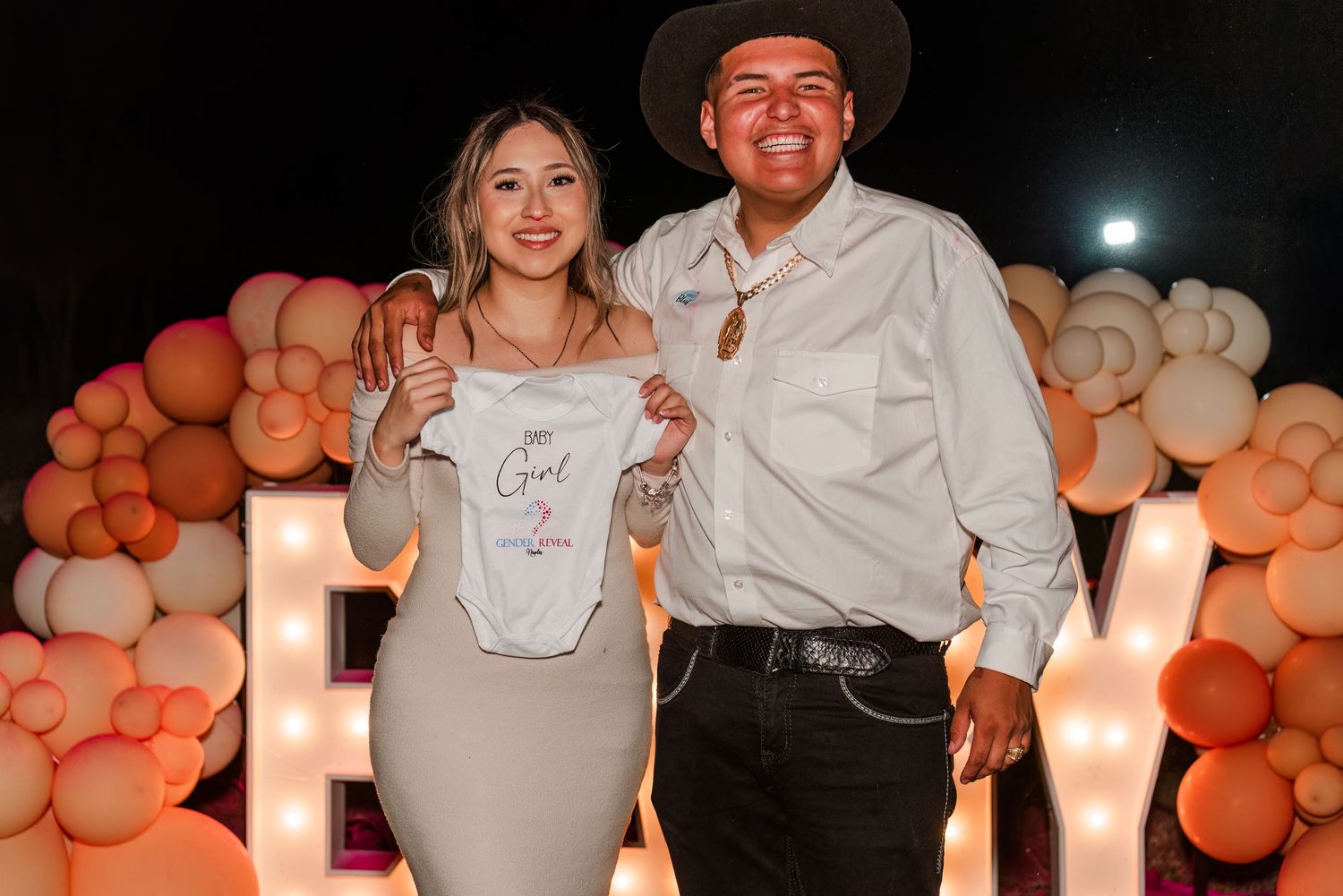 Couples pose together at a festive event decorated with orange balloons and warm lighting.