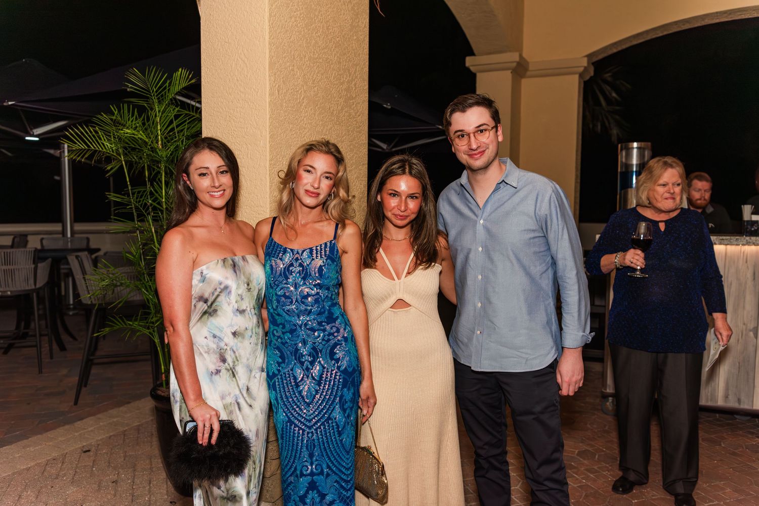 Group photo at a formal event with people wearing elegant attire including blue dresses and suits.