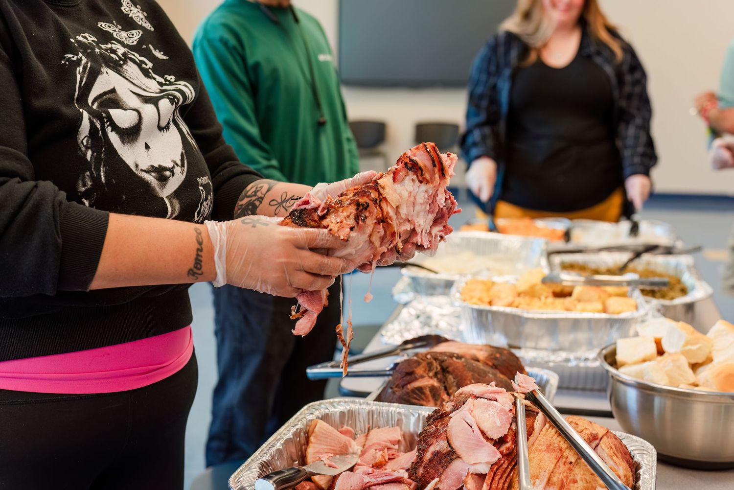 Someone carving a roasted turkey on a cutting board at what appears to be a holiday gathering or event.