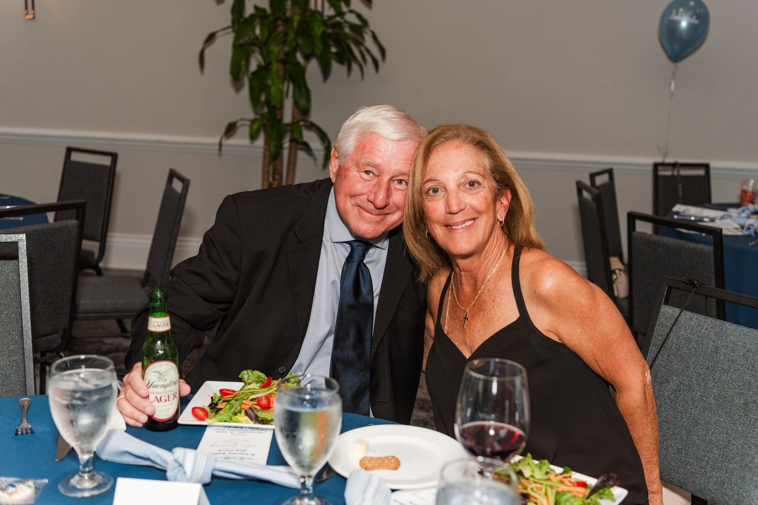 Guests enjoying a formal dinner event with table settings and drinks in an indoor venue.