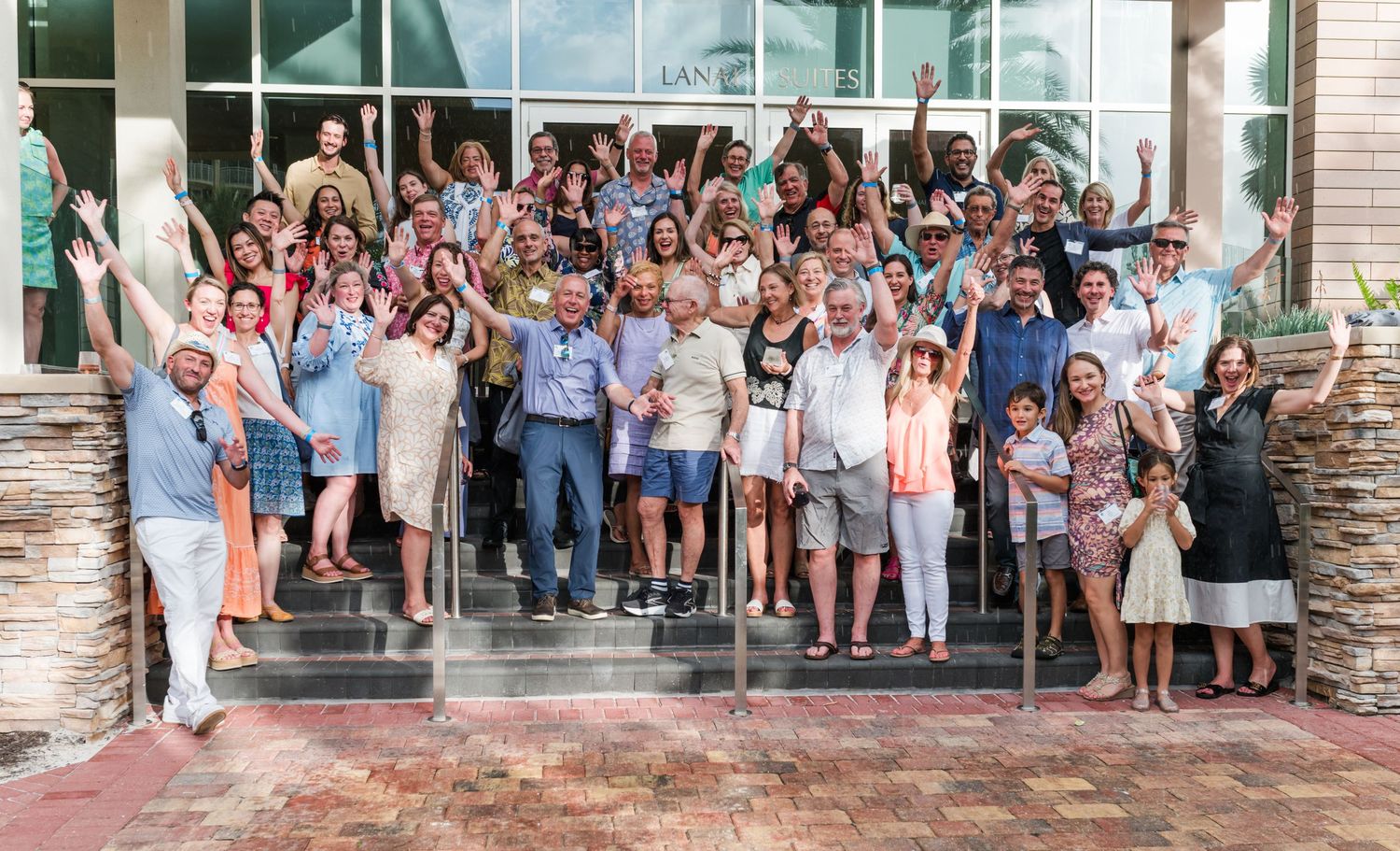 Large group of smiling people posing together on steps outside a modern building at a community event.