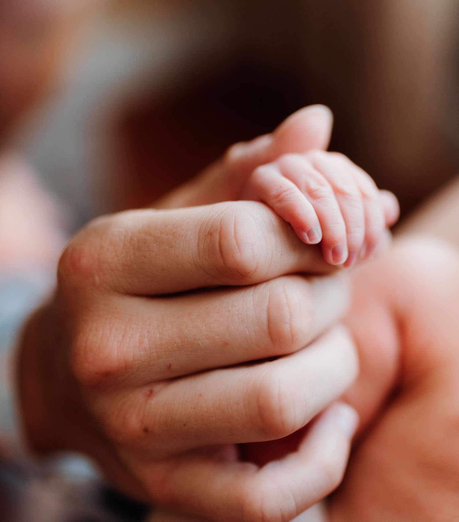 Close-up photo of two hands gently touching and intertwining in tender, intimate moment.