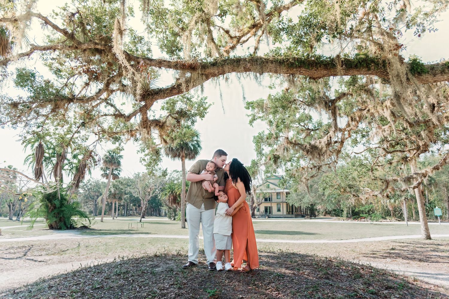 Couple sharing playful and intimate moments together under oak trees in an outdoor garden setting.