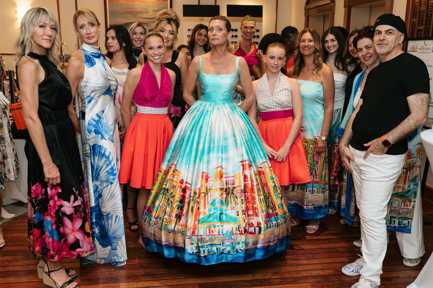 A group wearing colorful formal dresses with full skirts gather together at an indoor event.