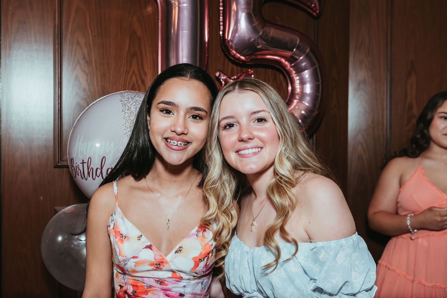 Group of friends celebrate at a party with glowing balloons and smiles in dimly lit venue.