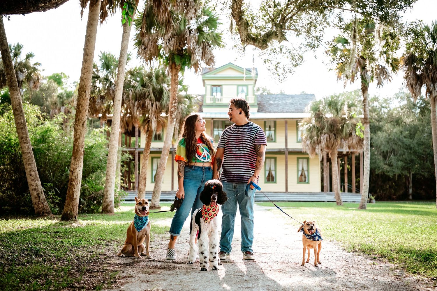 Family enjoying a walk together with their dog along a tree-lined path on a sunny afternoon.