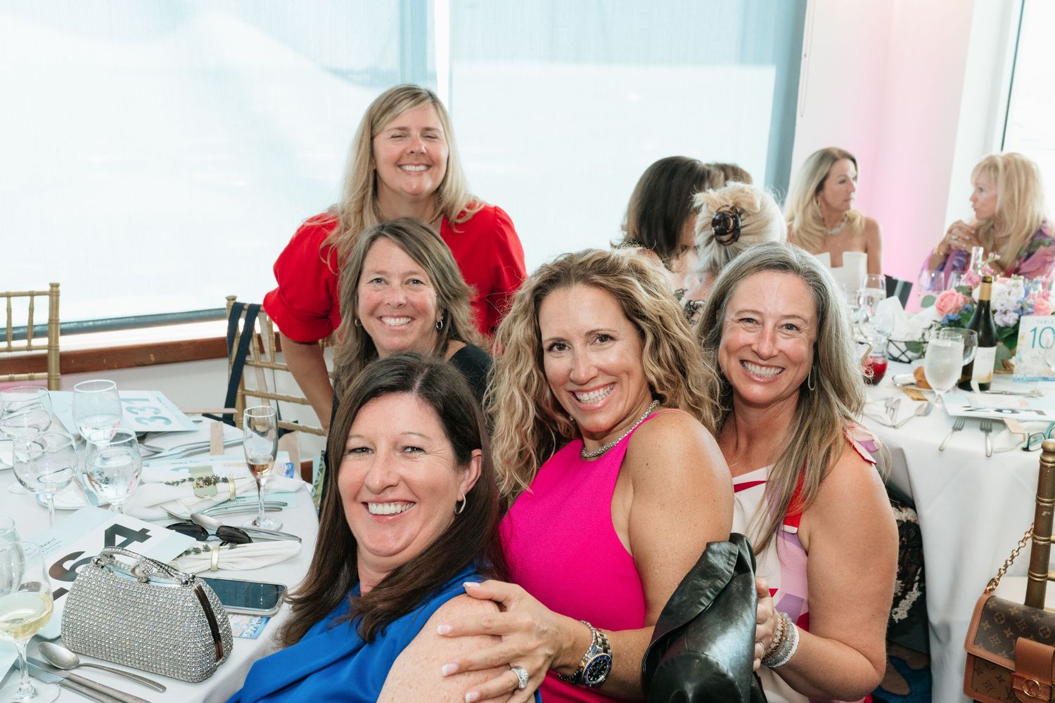 A group of people sit together at tables during a social gathering or celebration event.