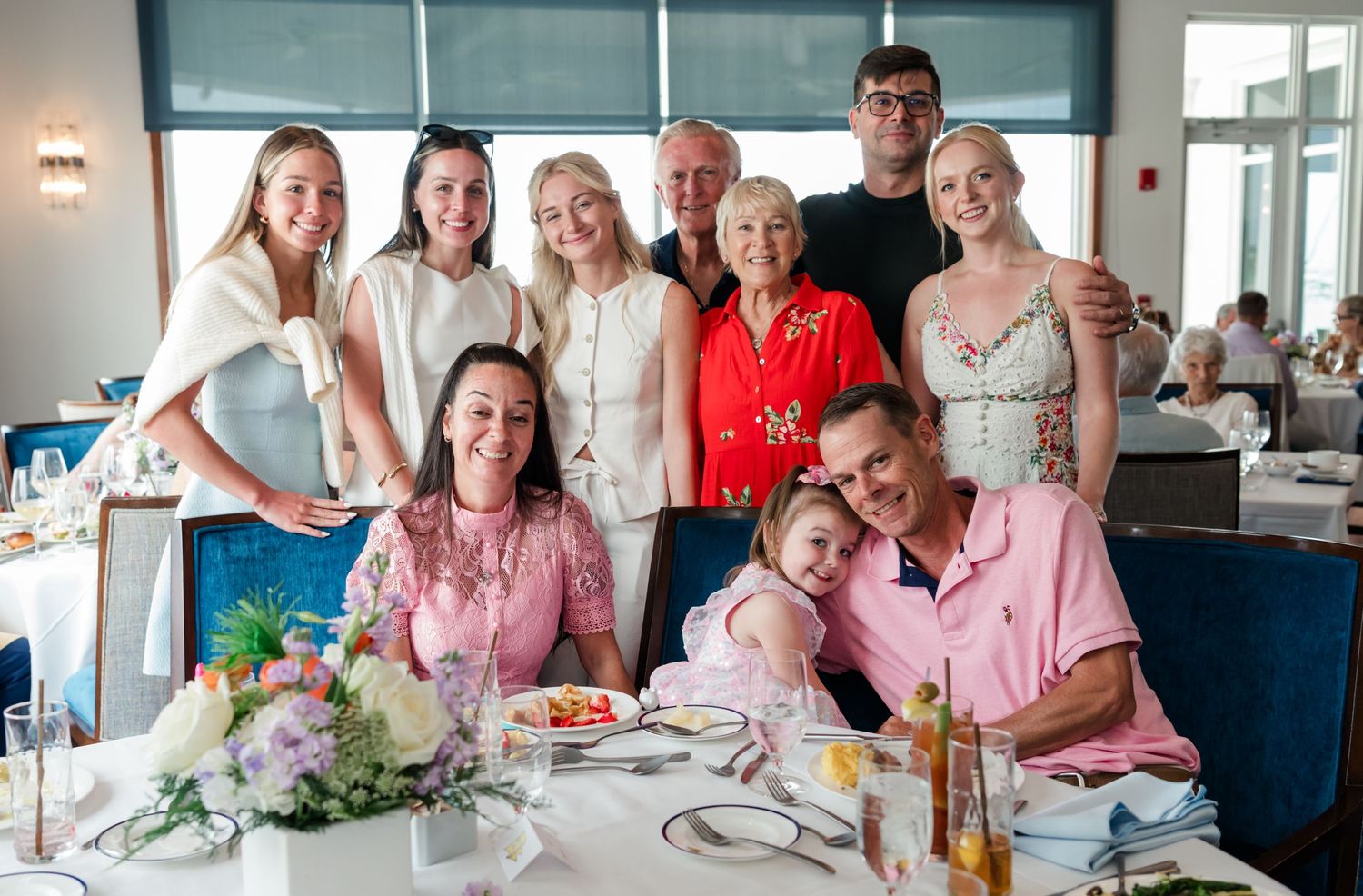 Large multigenerational family posing together at a restaurant table during a special celebration dinner.
