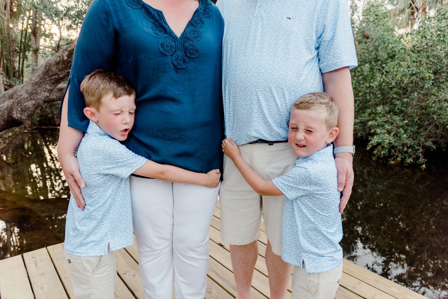 Family photos on dock show people in coordinated navy and light blue outfits creating a beautiful outdoor portrait setting.