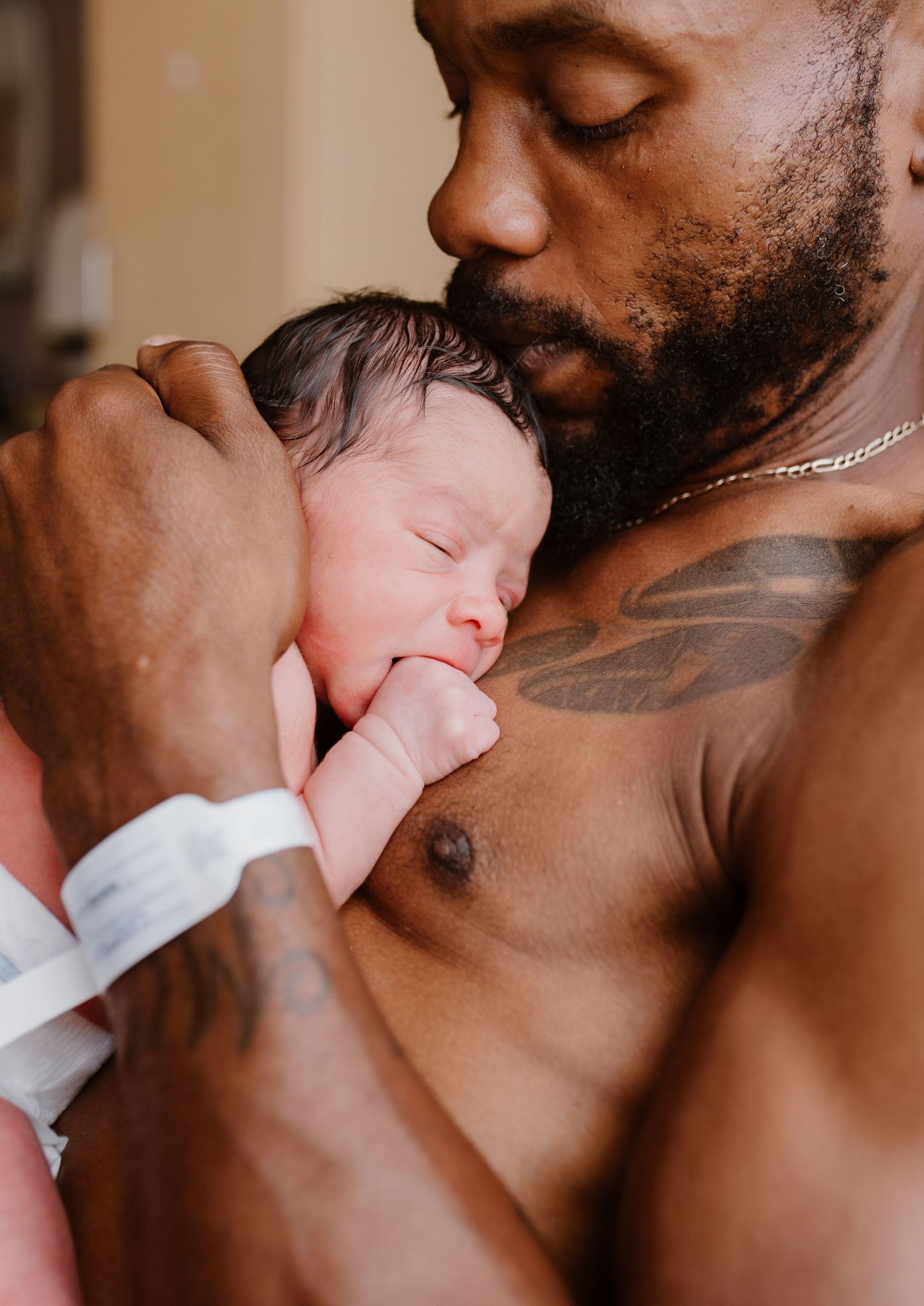 Intimate black and white portrait of a parent gently kissing and cradling a newborn baby.