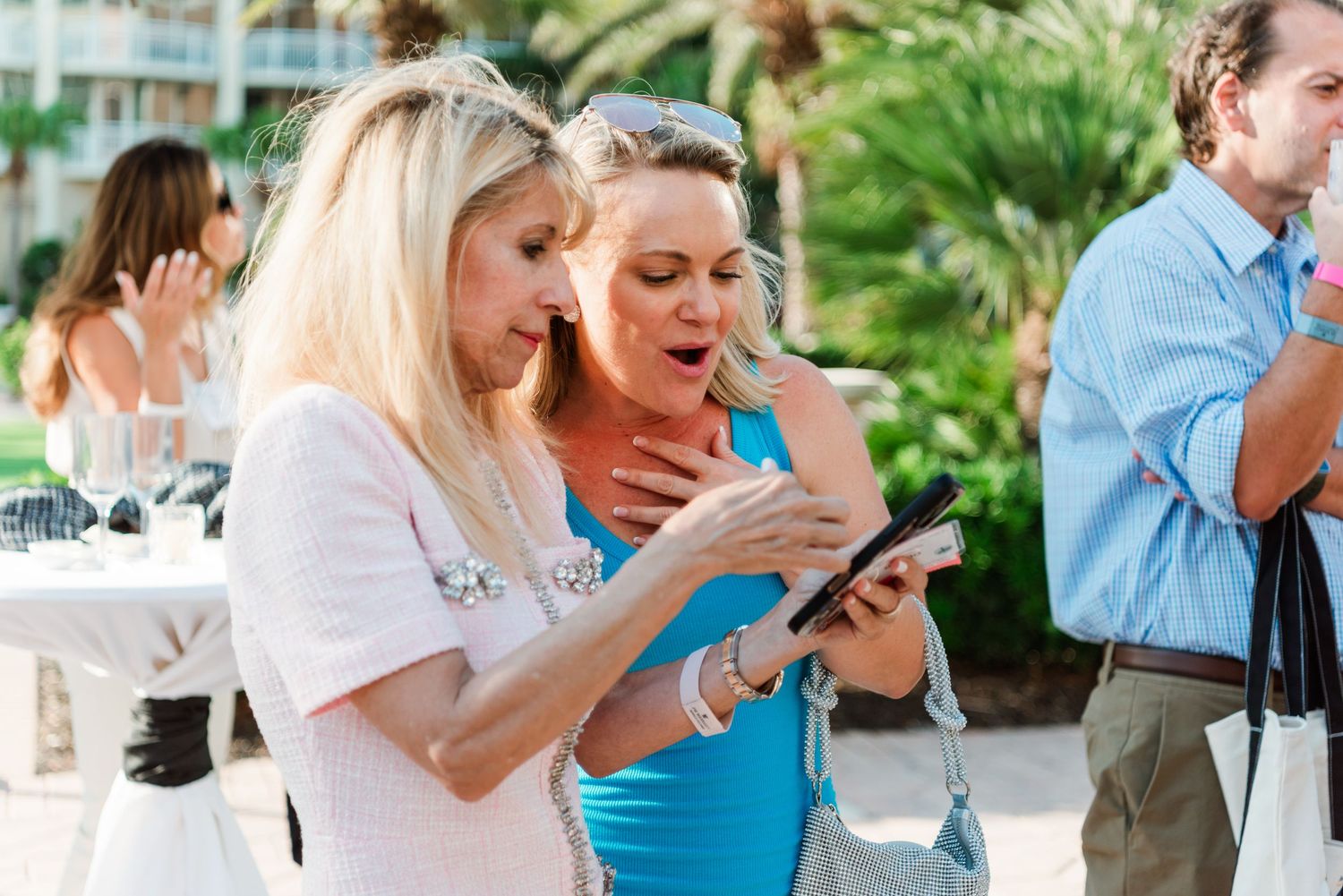 Two women looking at a mobile phone together during an outdoor social event.