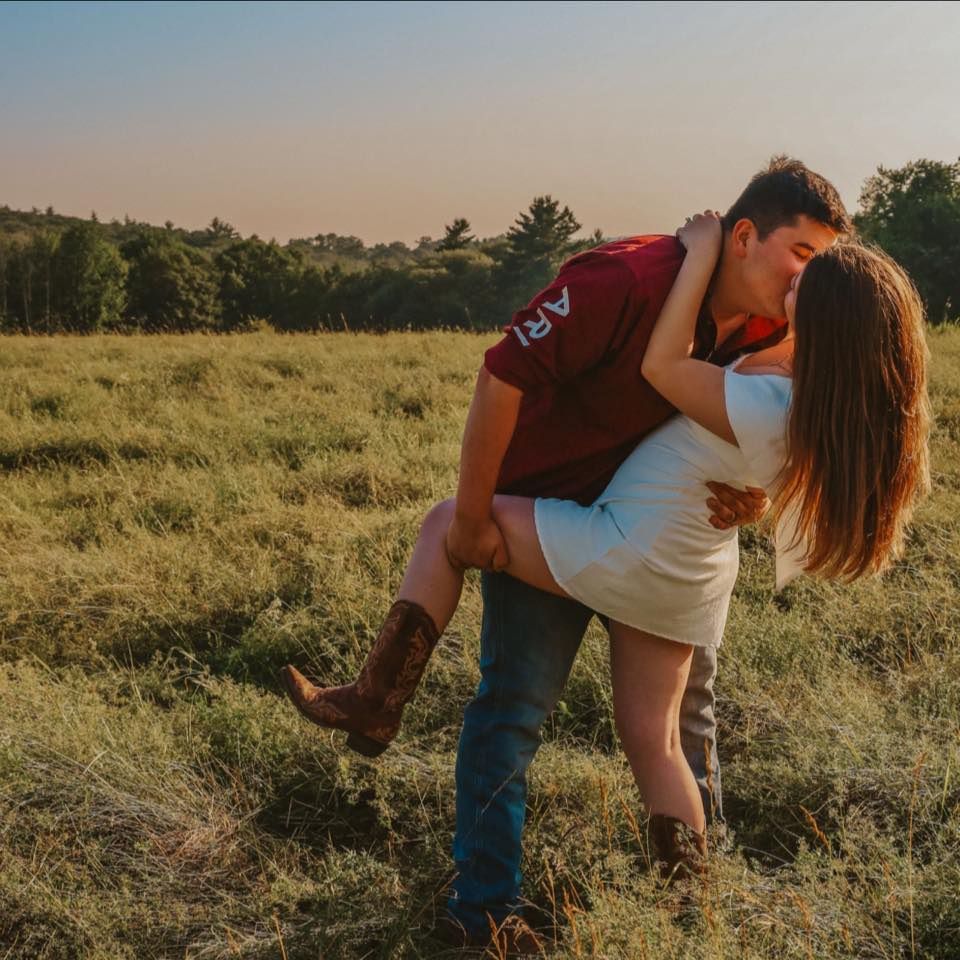 Romantic dip pose between couple in sunlit meadow at dusk.