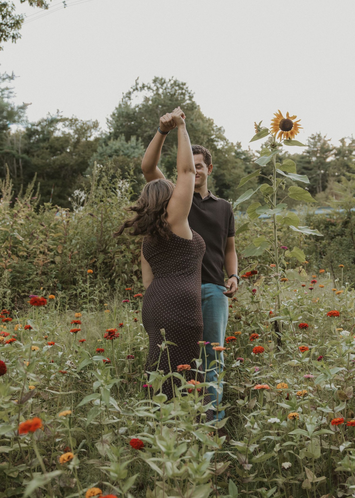 Couple dancing together in a vibrant flower garden with sunflowers and zinnias.